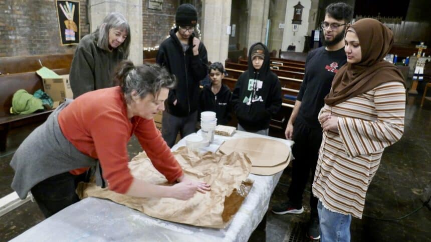 Lindsay teaches a group of people with kids and adults how to make paper mache flower petals